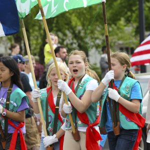 Girl Scouts marching in a parade with flags