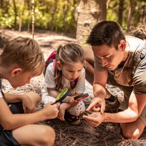 Kids exploring nature looking at bugs with a microscope with their scout leader